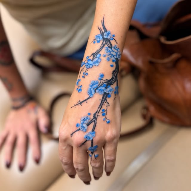 Blue cherry blossom branch tattoo on hand, Baton Rouge